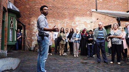 Visitors listening to the tour guide on the closed communal courtyard at Birmingham Back to Backs, West Midlands